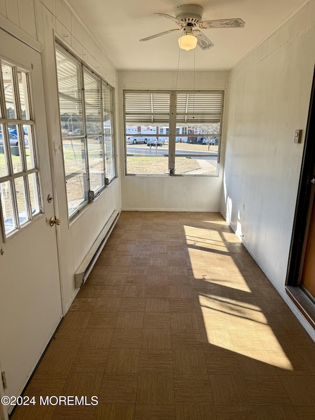 unfurnished sunroom with baseboard heating and ceiling fan