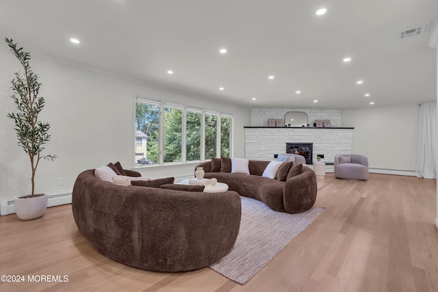 living room with a fireplace, light wood-type flooring, and a baseboard heating unit