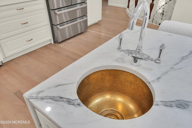 room details with stainless steel range, light wood-type flooring, white cabinetry, and light stone counters