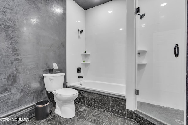 bathroom with tile walls, tiled shower / bath combo, and toilet