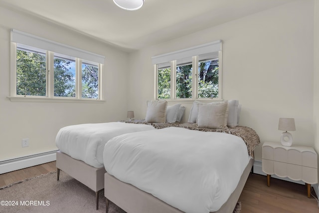 bedroom with baseboard heating, multiple windows, and dark wood-type flooring