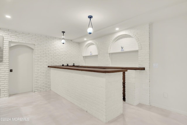 bar featuring pendant lighting and brick wall