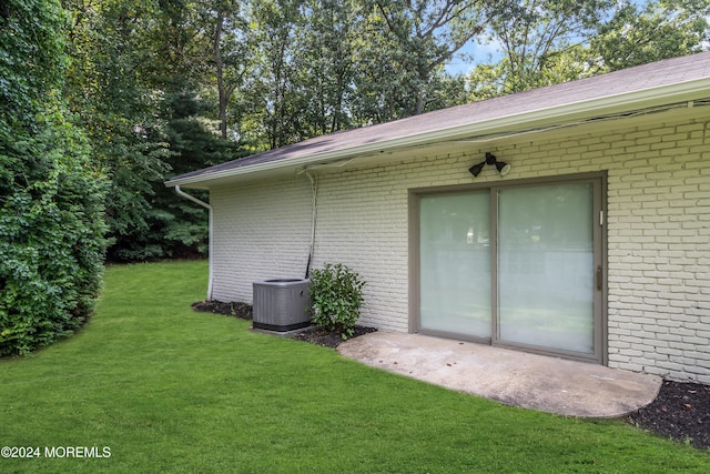 doorway to property featuring cooling unit and a lawn