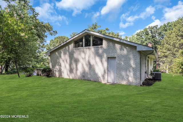 view of side of property with central AC unit and a yard