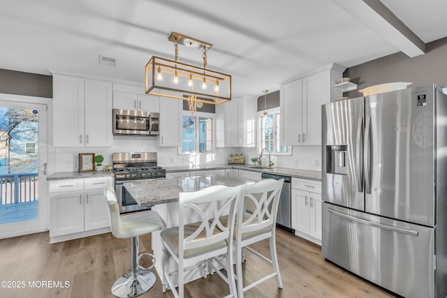 kitchen with appliances with stainless steel finishes, white cabinets, and decorative light fixtures