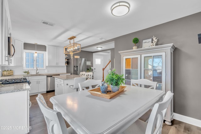 dining room featuring sink, a chandelier, a healthy amount of sunlight, and hardwood / wood-style floors