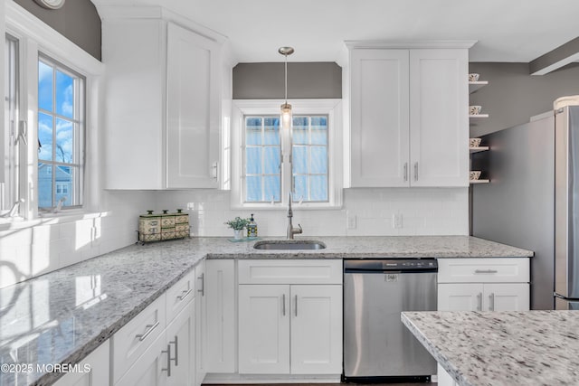 kitchen featuring light stone countertops, decorative light fixtures, stainless steel appliances, white cabinetry, and sink