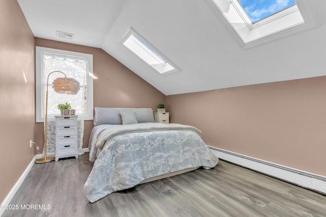 bedroom featuring wood-type flooring, baseboard heating, and vaulted ceiling with skylight