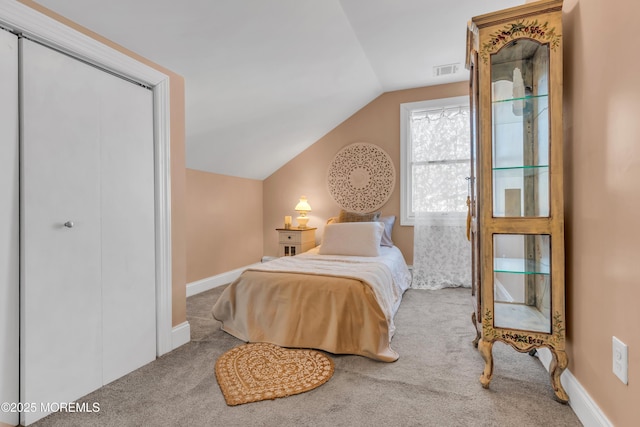 carpeted bedroom with a closet and vaulted ceiling