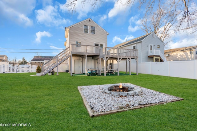 back of house featuring an outdoor fire pit, a yard, and a wooden deck