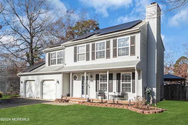 view of front of house with covered porch, solar panels, a garage, and a front yard