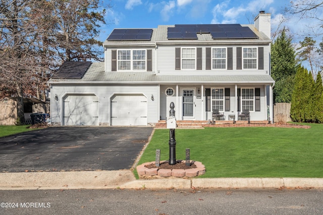 view of front of home featuring solar panels, a garage, covered porch, and a front lawn