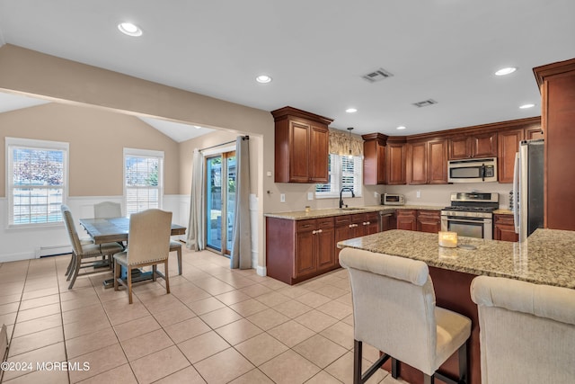 kitchen with lofted ceiling, sink, appliances with stainless steel finishes, decorative light fixtures, and a healthy amount of sunlight