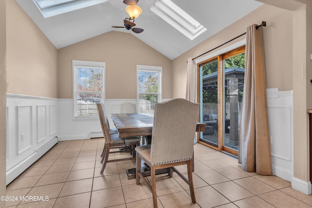 dining area with ceiling fan, vaulted ceiling with skylight, light tile patterned floors, and a baseboard heating unit