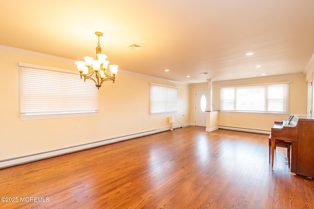 spare room featuring baseboard heating, ornamental molding, a chandelier, and hardwood / wood-style flooring