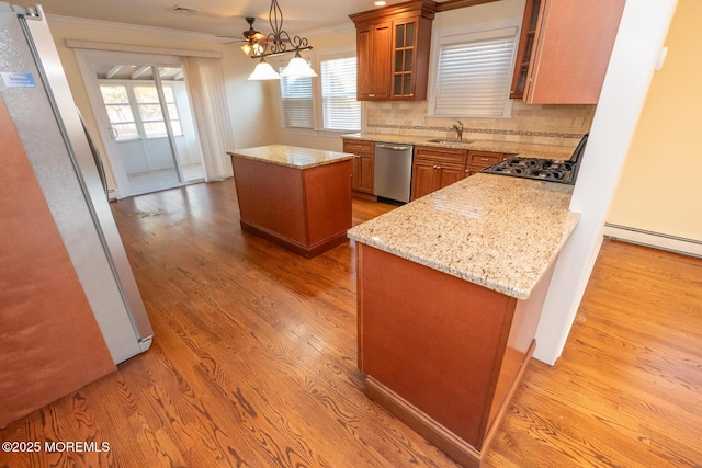 kitchen with stainless steel appliances, light stone countertops, a kitchen island, and sink