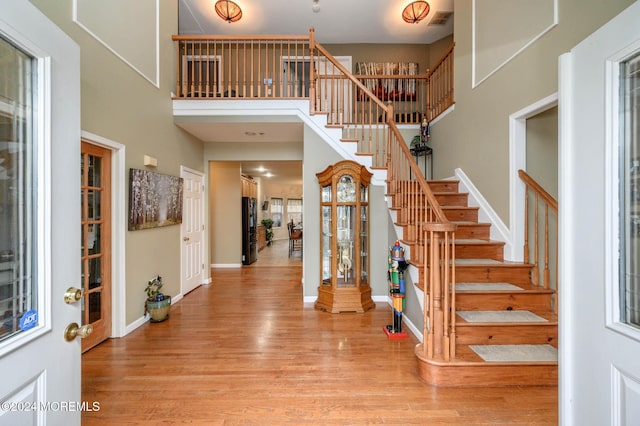 foyer entrance with a towering ceiling, hardwood / wood-style flooring, and a wealth of natural light