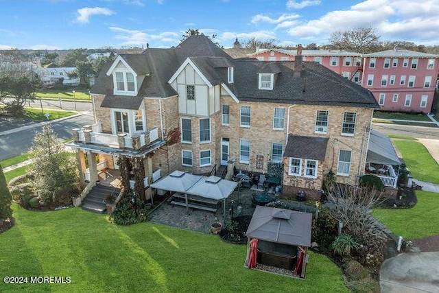 back of house featuring a balcony and a yard