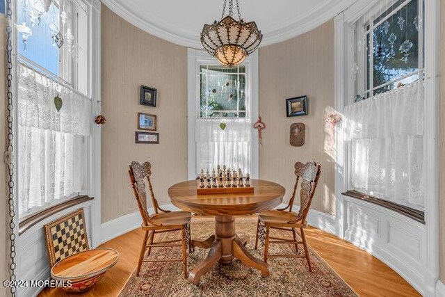 dining room featuring a notable chandelier, ornamental molding, and light hardwood / wood-style flooring