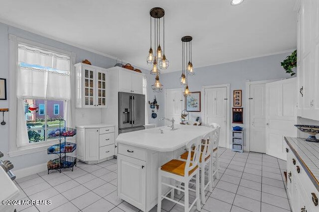 kitchen featuring high end fridge, a kitchen bar, white cabinets, and a kitchen island with sink