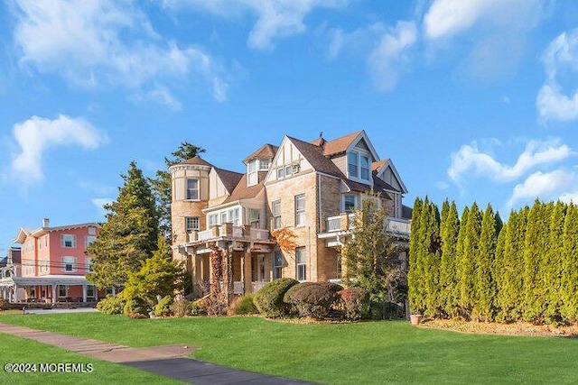 view of front of house featuring a balcony and a front lawn