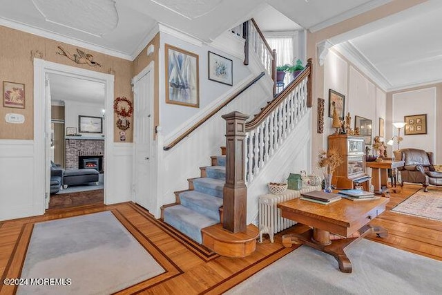 staircase with a fireplace, wood-type flooring, radiator, and ornamental molding