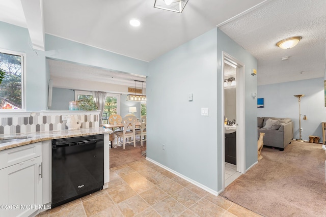 kitchen featuring pendant lighting, dishwasher, light carpet, white cabinets, and a textured ceiling