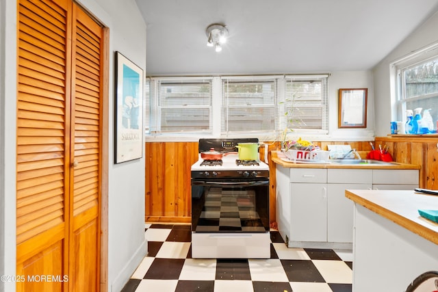 kitchen featuring white cabinets, white gas range, a healthy amount of sunlight, and sink