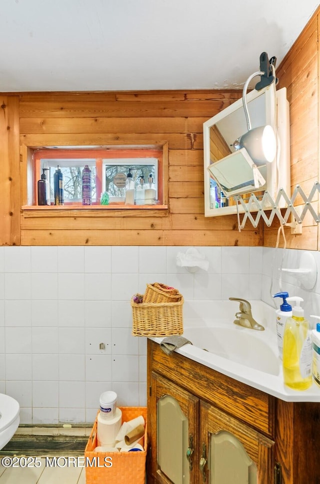 bathroom featuring tile patterned flooring, vanity, toilet, and wooden walls