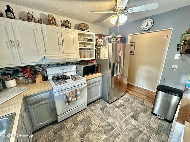 kitchen featuring ventilation hood, stainless steel refrigerator with ice dispenser, white gas range, tasteful backsplash, and white cabinetry