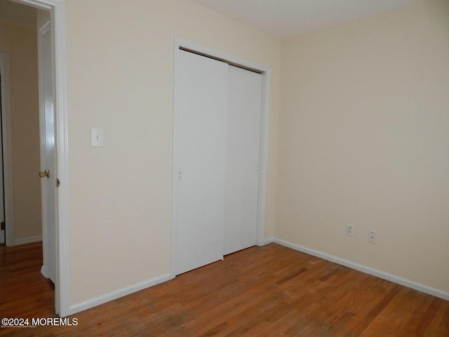 unfurnished bedroom featuring wood-type flooring and a closet