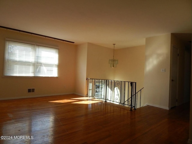 unfurnished room featuring a chandelier and dark wood-type flooring