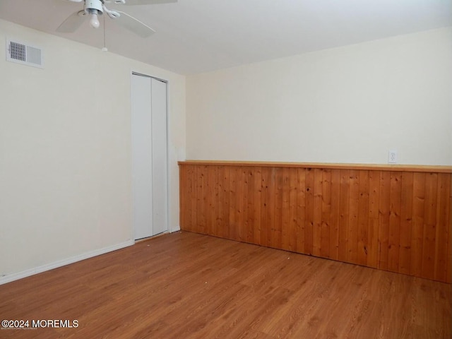 spare room featuring wood walls, ceiling fan, and hardwood / wood-style flooring