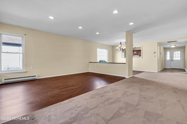 unfurnished room with hardwood / wood-style floors, baseboard heating, and a chandelier