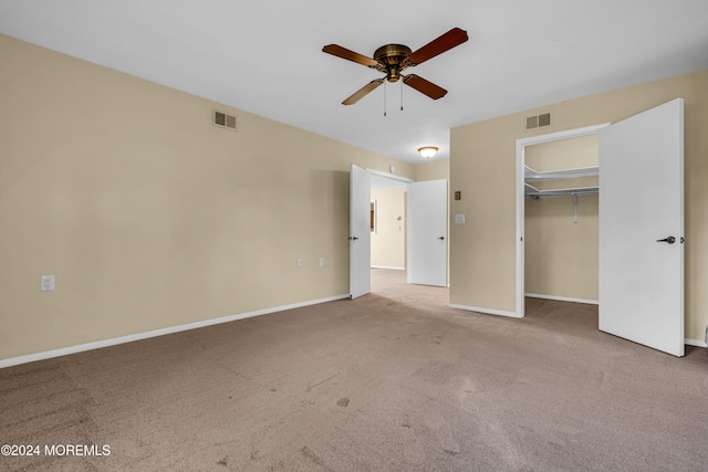 unfurnished bedroom featuring carpet, a closet, a spacious closet, and ceiling fan