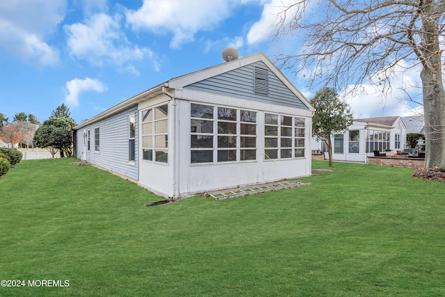 view of side of home with a sunroom and a yard