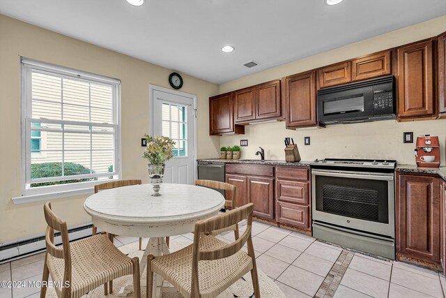 kitchen featuring stainless steel range, light tile patterned floors, a baseboard radiator, and sink