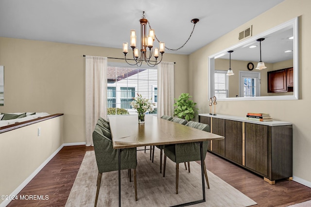 dining room with dark hardwood / wood-style floors and an inviting chandelier