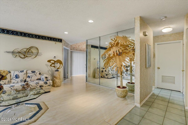 corridor featuring light tile patterned flooring and a textured ceiling