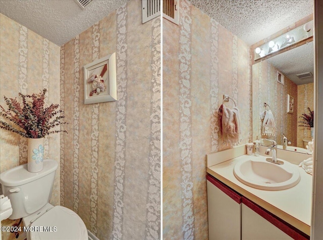 bathroom with vanity, toilet, and a textured ceiling