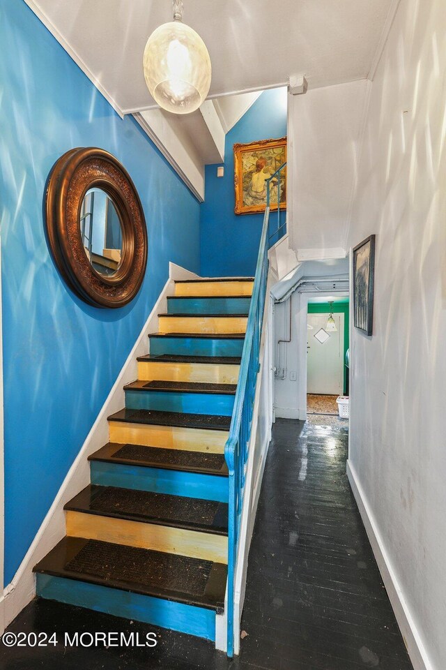 stairway with wood-type flooring and ornamental molding