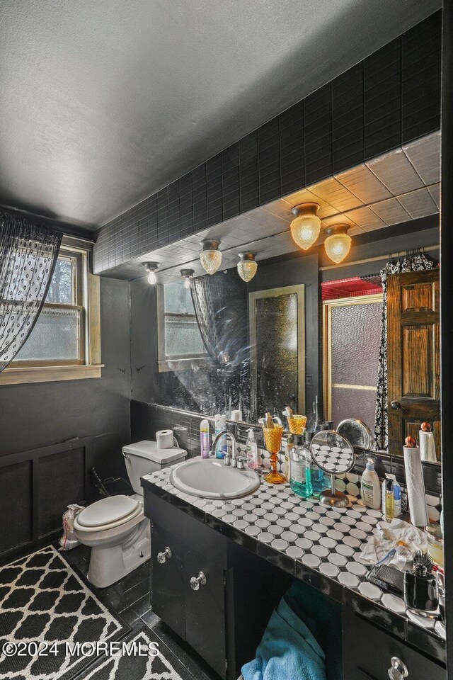 bathroom featuring tile patterned floors, vanity, toilet, and walk in shower