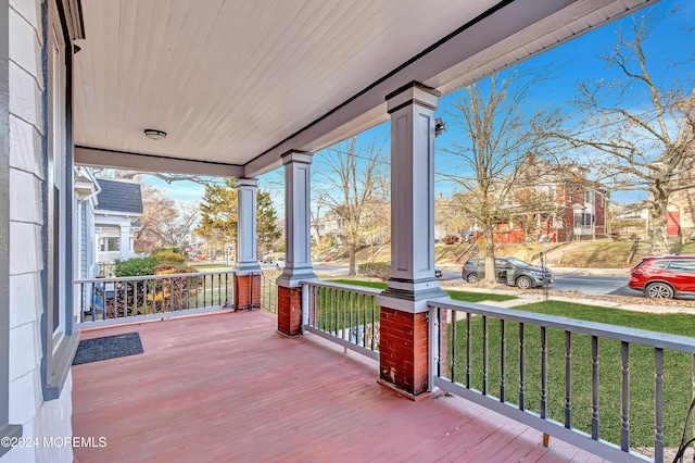 wooden terrace featuring covered porch and a lawn