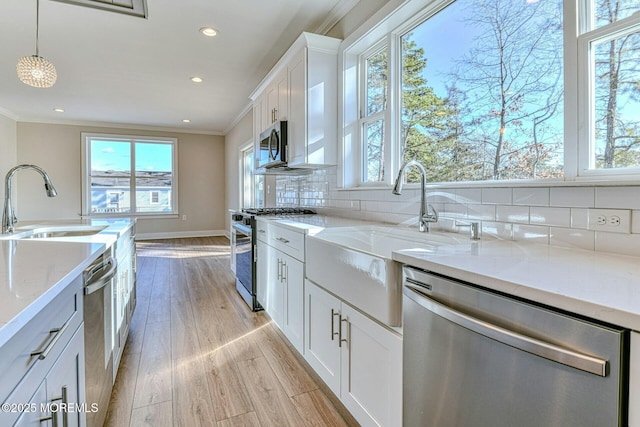 kitchen with white cabinetry, stainless steel appliances, light stone counters, pendant lighting, and decorative backsplash