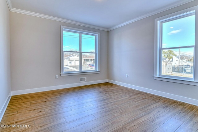 empty room with light hardwood / wood-style floors and crown molding