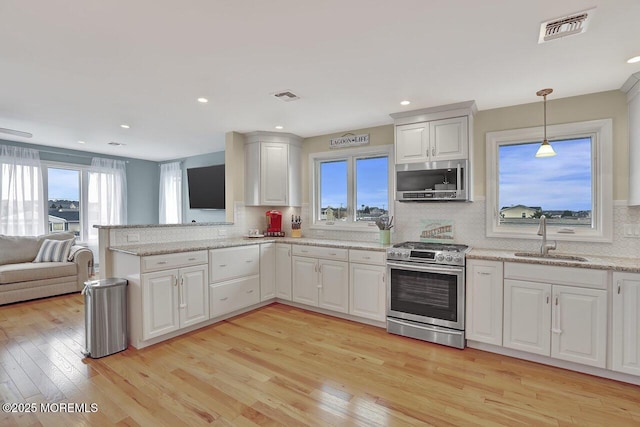 kitchen featuring white cabinetry, sink, stainless steel appliances, and light wood-type flooring