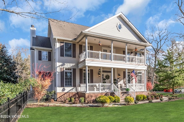 view of front of property featuring covered porch, a balcony, and a front yard