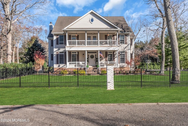 view of front of house featuring a porch, a balcony, and a front lawn