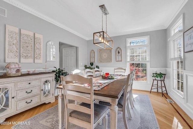 dining room with light wood-type flooring, ornamental molding, and a chandelier