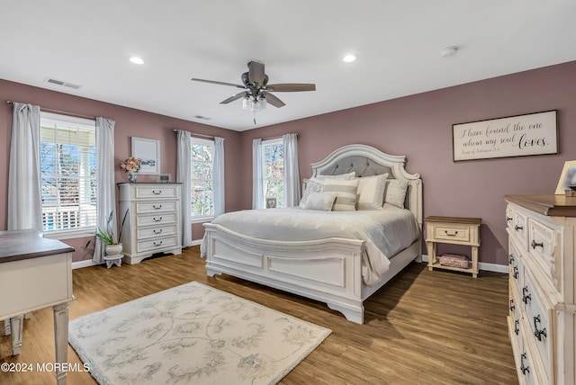 bedroom with hardwood / wood-style floors, ceiling fan, and multiple windows